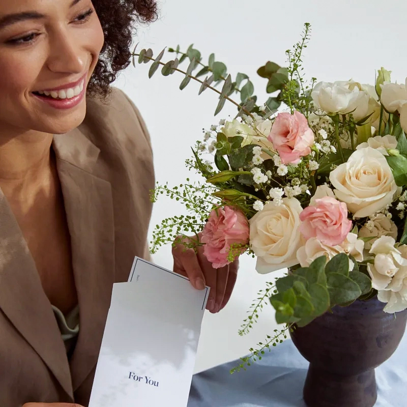 Foto de uma moça olhando para um vaso de flores